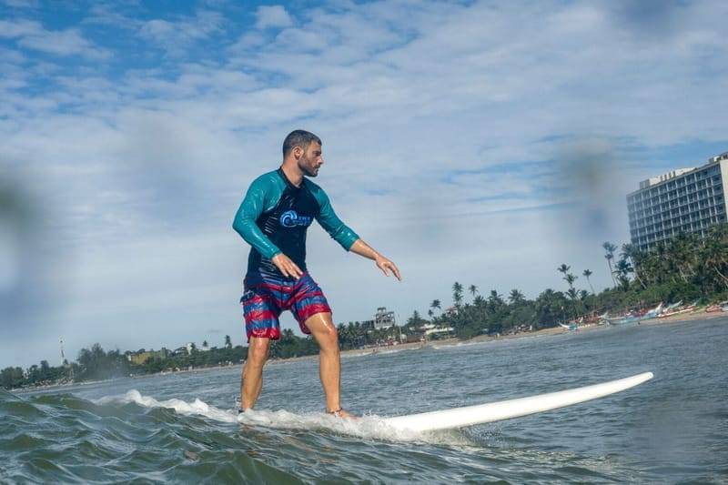 A surfer riding a longboard along the Weligama coastline, Sri Lanka