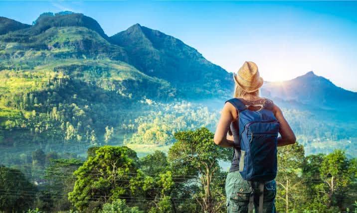 A traveller with a backpack looking out over Sri Lanka's green hill country