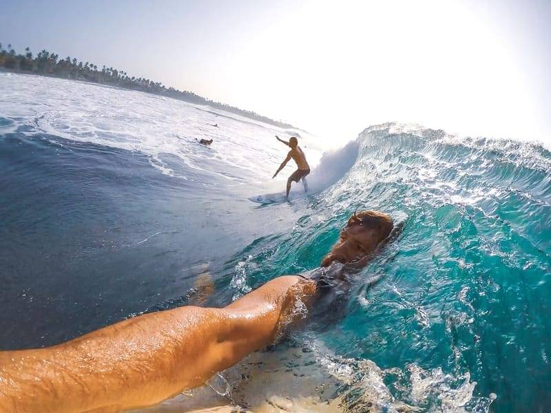 Point-of-view shot from a surfboard as another surfer rides the same wave — surf etiquette in practice