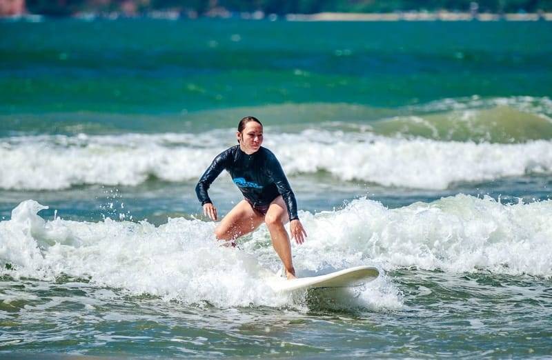 A surfer in a blue rash guard riding whitewater at Weligama Bay