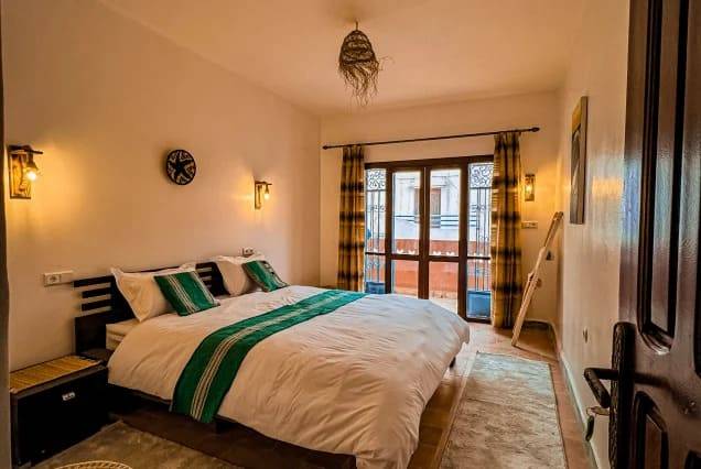 Private ensuite room with a double bed and balcony doors at The Surfer SurfStyle Camp, Tamraght – photo 1
