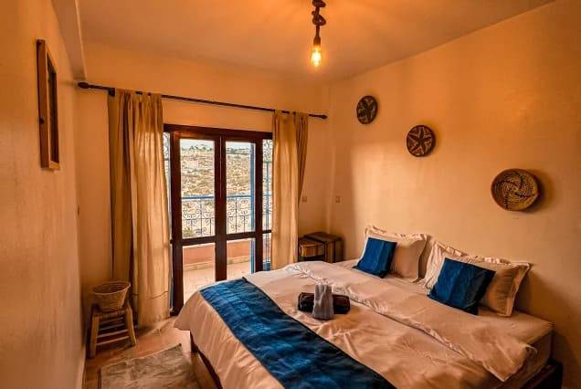Private ensuite room with a double bed and balcony doors at The Surfer SurfStyle Camp, Tamraght – photo 2