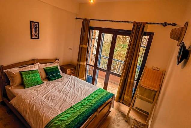 Private ensuite room with a double bed and balcony doors at The Surfer SurfStyle Camp, Tamraght – photo 4