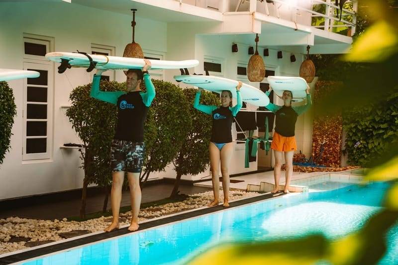 Guests carrying surfboards past the pool at The Surfer Beach Camp, Weligama, Sri Lanka
