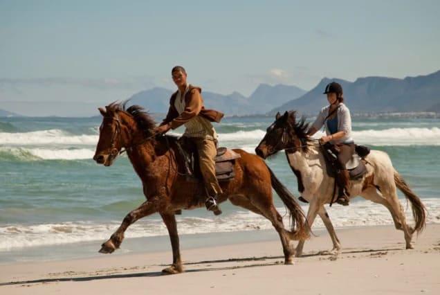 Two riders on horseback along the beach at Tamraght, Morocco