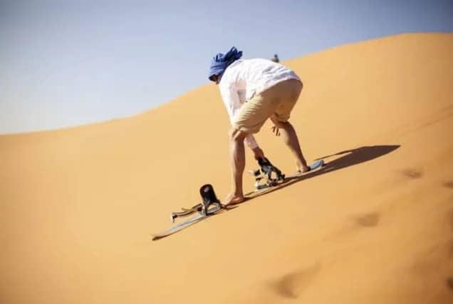 A sandboarder riding down a dune near Taghazout, Morocco