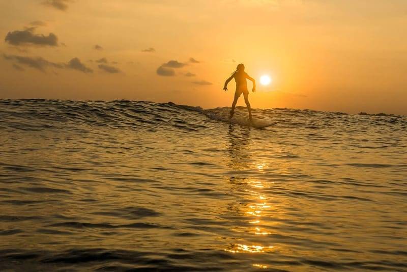 Silhouette of a surfer riding a wave at sunset off Sri Lanka’s south coast